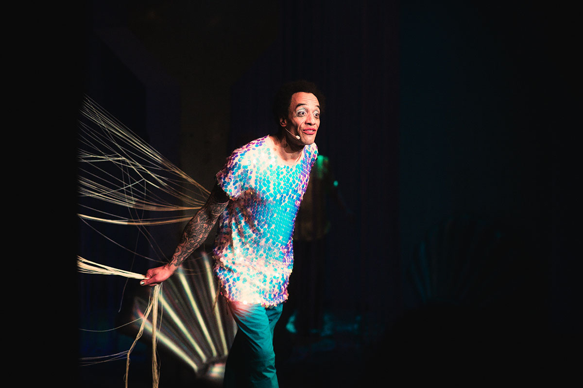 Schauspieler Patrice Lipeb in schillerndem Kostüm während der Performance SOFT WAR im PATHOS THEATER inmitten des aufwändigen Bühnenbildes